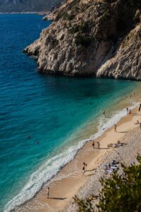 Beautiful aerial shot of Kaputaş Beach in Kaş, Turkey, showcasing cliffs, turquoise water, and beachgoers.