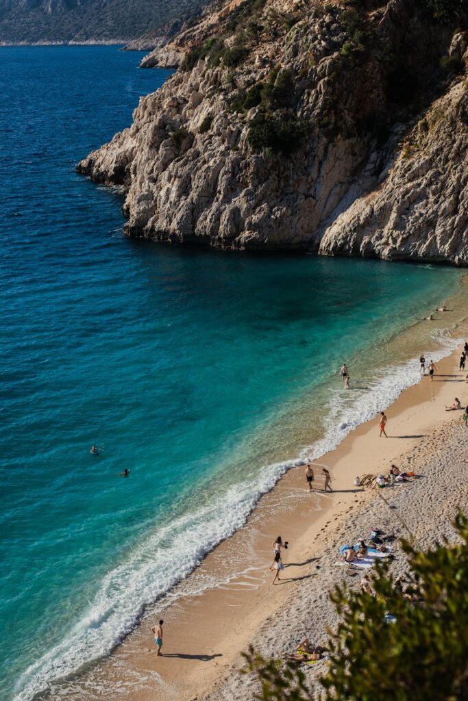 Beautiful aerial shot of Kaputaş Beach in Kaş, Turkey, showcasing cliffs, turquoise water, and beachgoers.